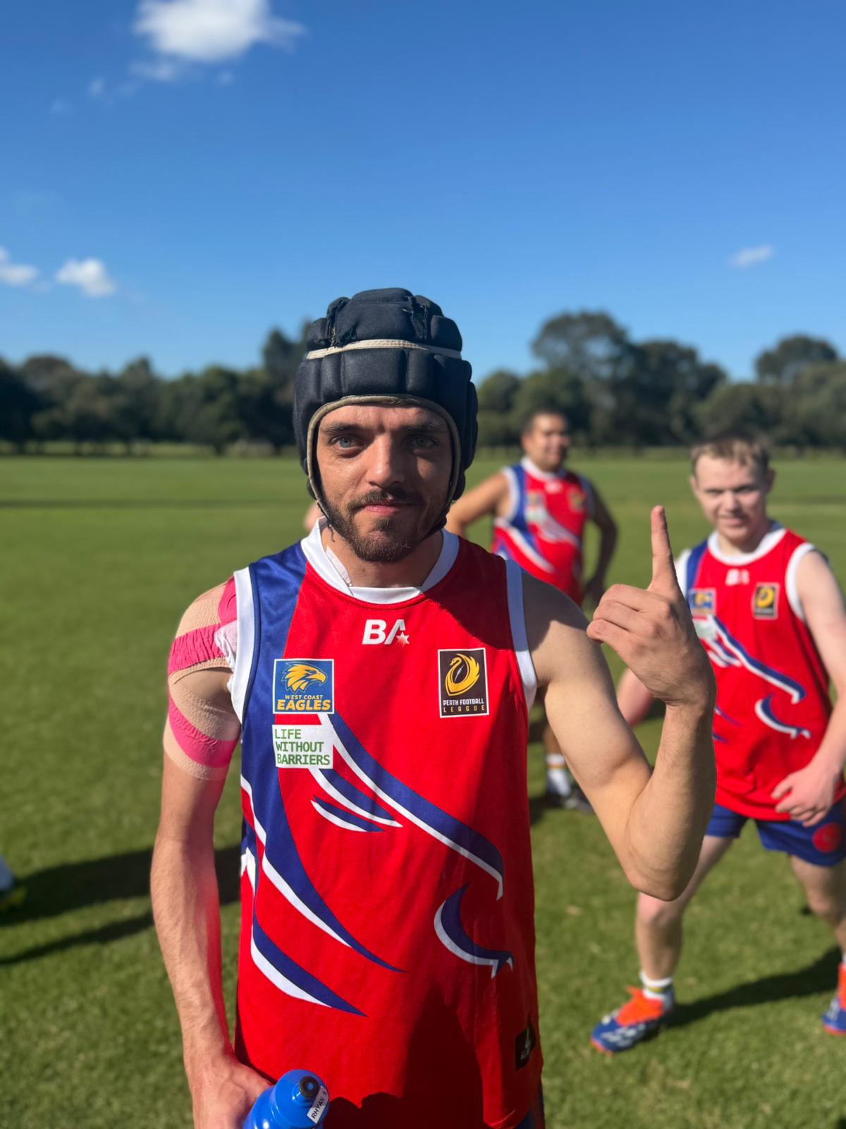 Hale Foundation participant in AFL jersey giving a thumbs up on the football oval